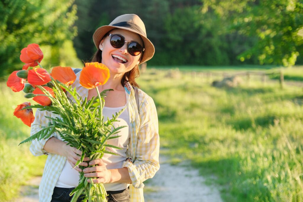 Portrait of beautiful mature healthy happy woman with bouquet of poppies